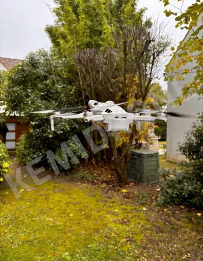 Drone blanc volant dans un jardin vert.
