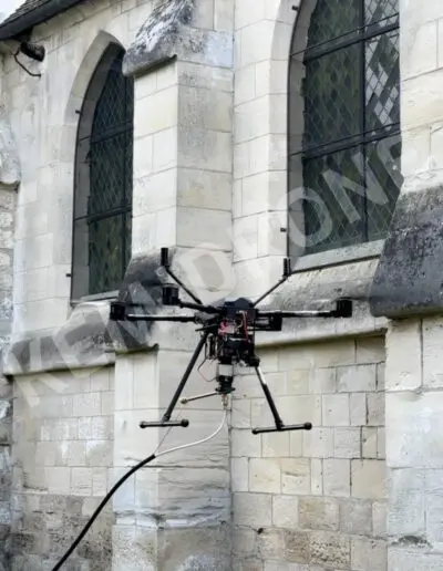 Drone inspectant un mur d'église en pierre.