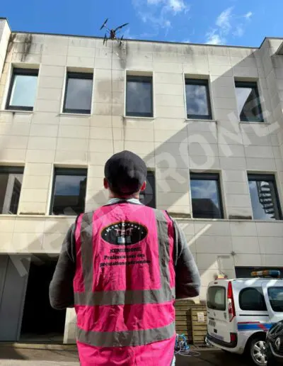 Homme contrôlant un drone près d'un bâtiment.