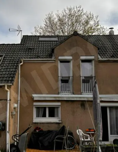 Maison en ardoise avec mobilier extérieur.