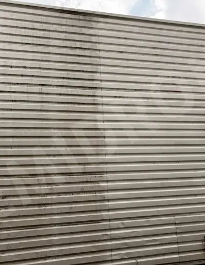 Mur blanc en tôle ondulée, rouille visible.