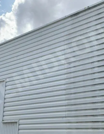 Mur en métal ondulé sous ciel nuageux.