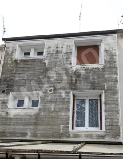 Façade de maison avec traces d'humidité visibles.