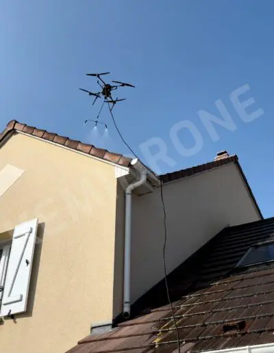 Drone nettoyant le toit d'une maison ensoleillée.