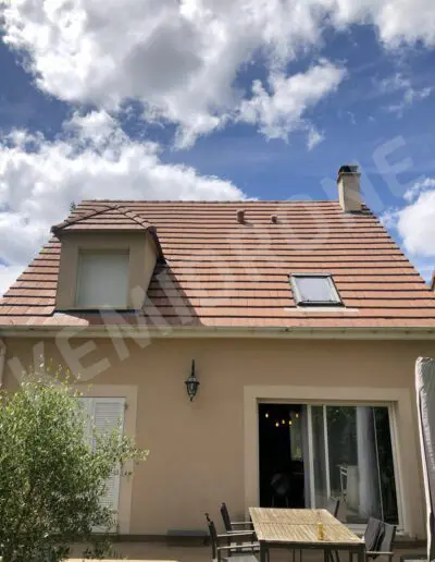 Maison avec terrasse et ciel bleu.