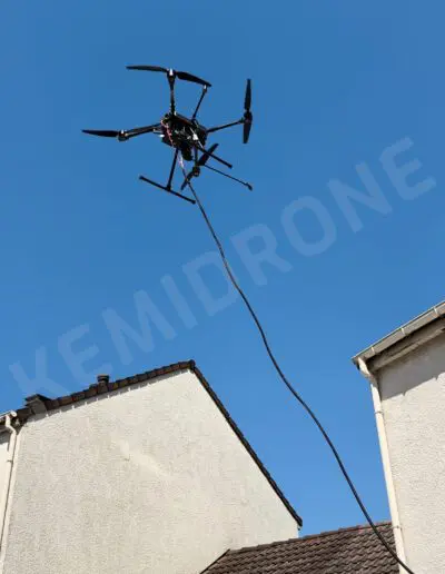Drone volant au-dessus des maisons sous ciel bleu.