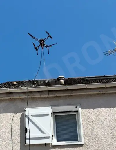 Drone coincé sur un toit sous ciel bleu.